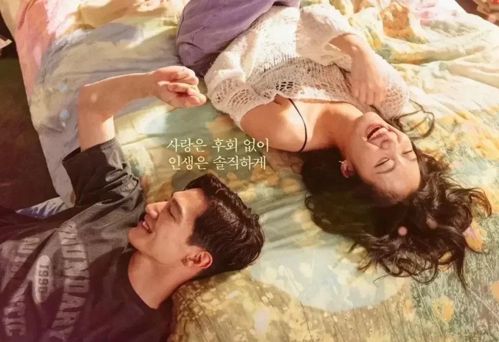Cena de Regras do Amor na Cidade Grande: Kim Go-eun e Steve Sanghyun Noh em cena do filme Regras do Amor na Cidade Grande. Os dois aparecem deitados lado a lado sobre uma cama, sorrindo e conversando em um momento descontraído.